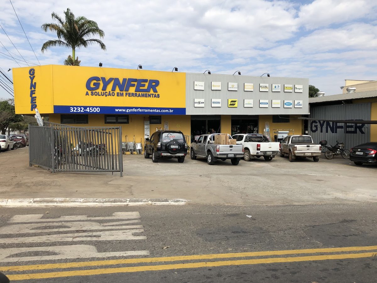 Fachada da loja Gynfer em Goiânia, com o letreiro amarelo e as caminhonetes de clientes carregando material no pátio